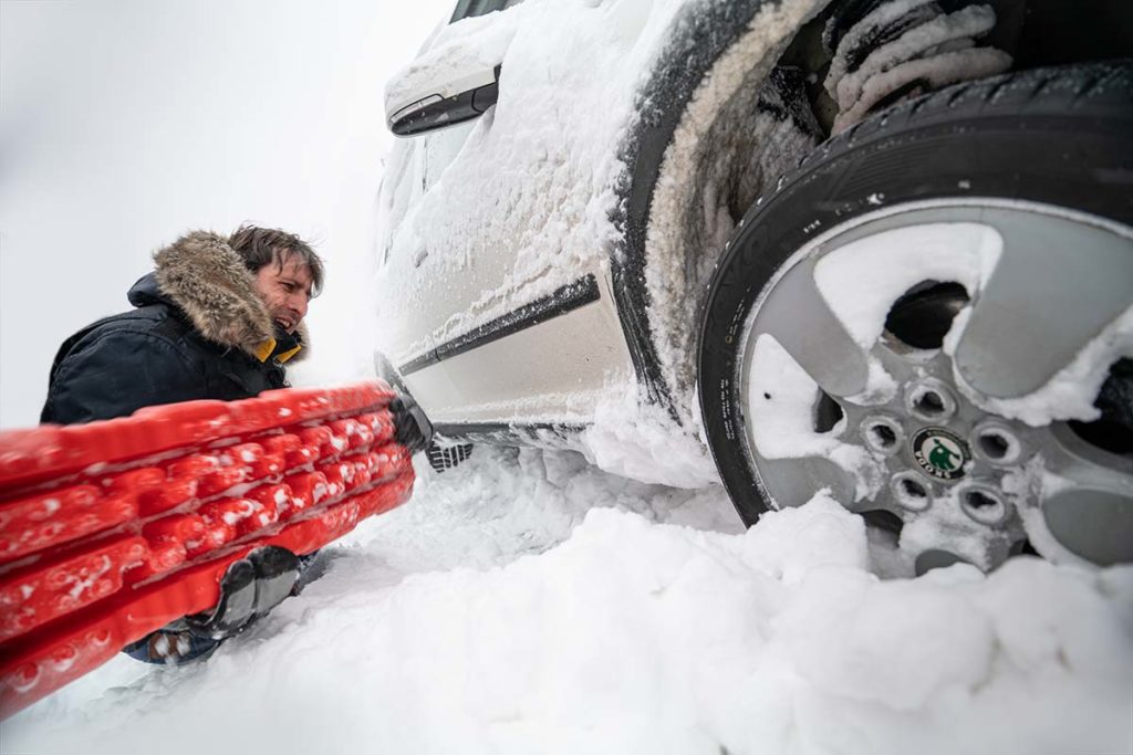 Auto mit Hilfe von Bergebrettern aus dem Schnee befreien