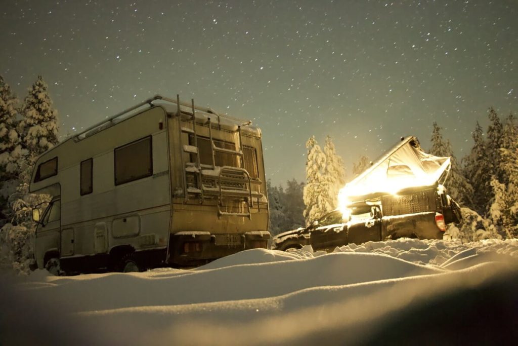 Nachtaufnahme mit Sternenhimmel von wei Campern im Schnee