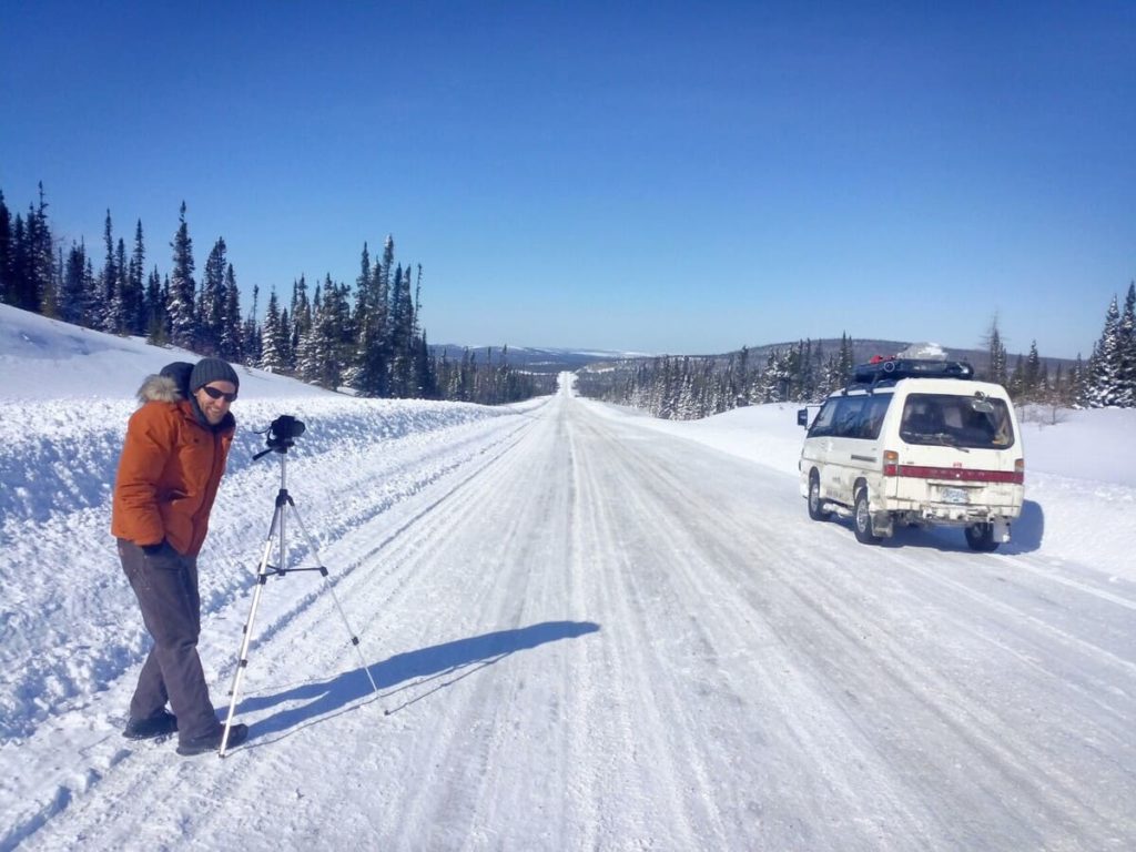 tigerexped Techniker beim Fotografieren seines Mitsubishi L300 Campervans auf einer verscheiten kanadischen Landstraße