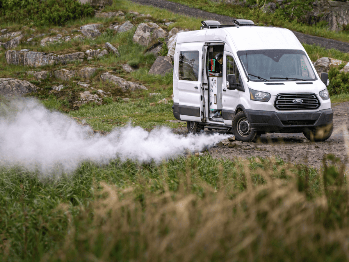 Weißer Camper mit deutlicher weißer Qualmbildung unter dem Fahrzeug aus dem Auspuff der Standheizung
